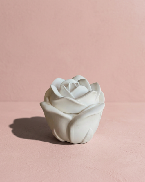 Vela artesanal Rose en recipiente blanco con forma de rosa y tapa floral decorativa.