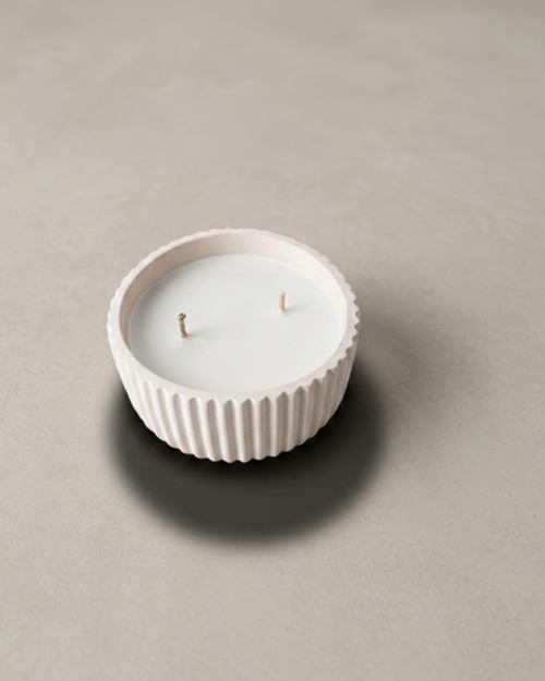 Vela artesanal Serena en recipiente blanco redondo, acanalado y de diseño minimalista.