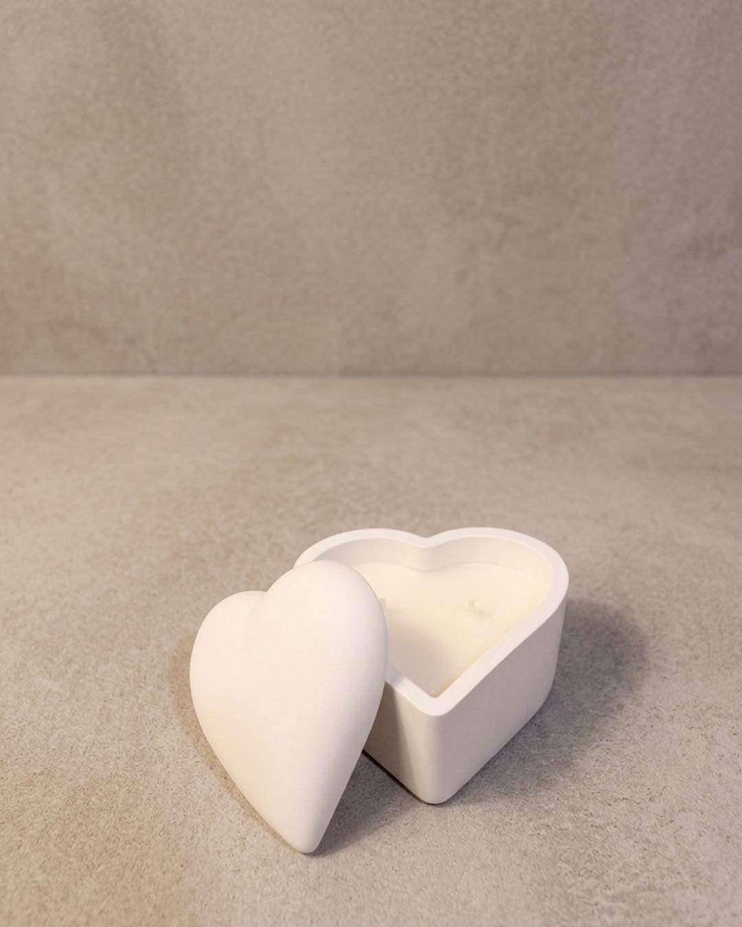 Vela artesanal Cofre Corazón en recipiente blanco con forma de corazón y tapa.
