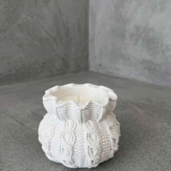 Vela artesanal Lana en recipiente blanco con textura de punto y tejido trenzado.
