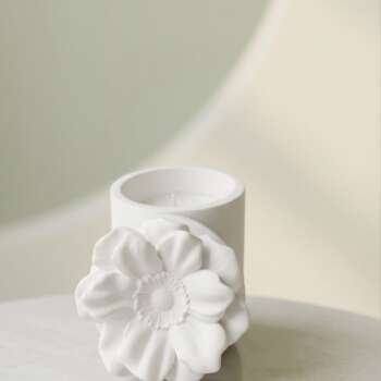 Vela artesanal Magnolia en un recipiente floral blanco de yeso con tapa.