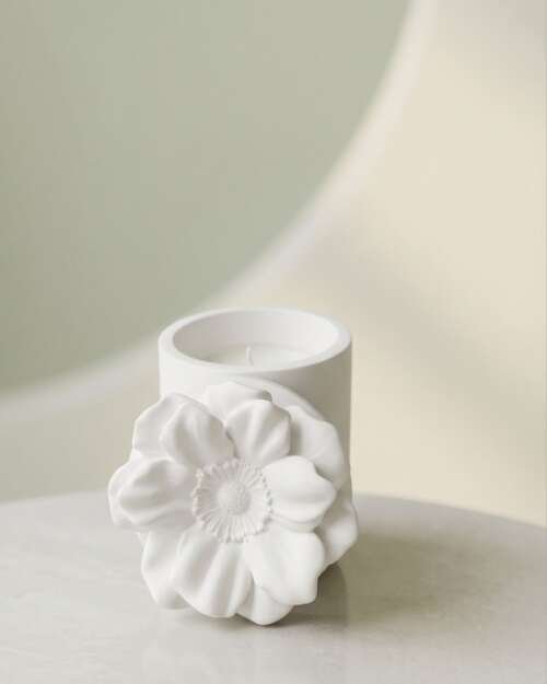 Vela artesanal Magnolia en un recipiente floral blanco de yeso con tapa.