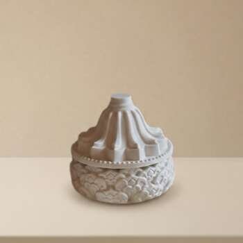Vela artesanal Nimbo en un pequeño recipiente blanco con tapa ornamental.