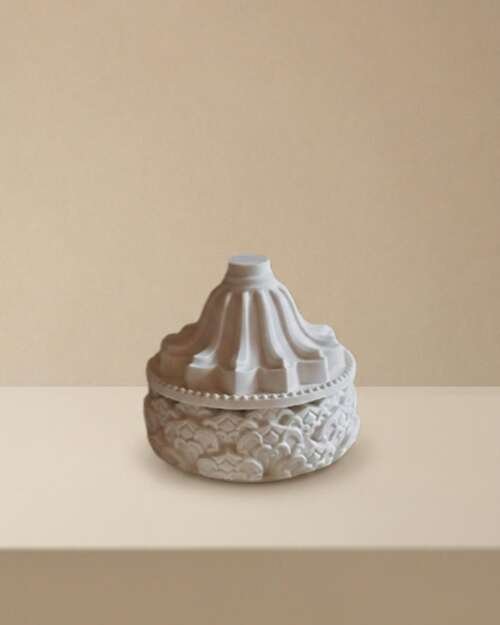 Vela artesanal Nimbo en un pequeño recipiente blanco con tapa ornamental.